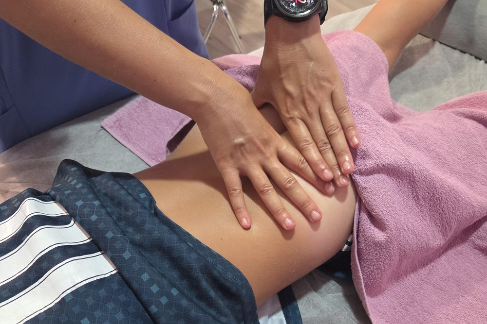 Fisioterapeuta de Kineos tratando con las manos la zona lumbar de un paciente en el Ensanche de Vallecas